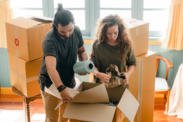 Two people wrapping items and putting them into boxes